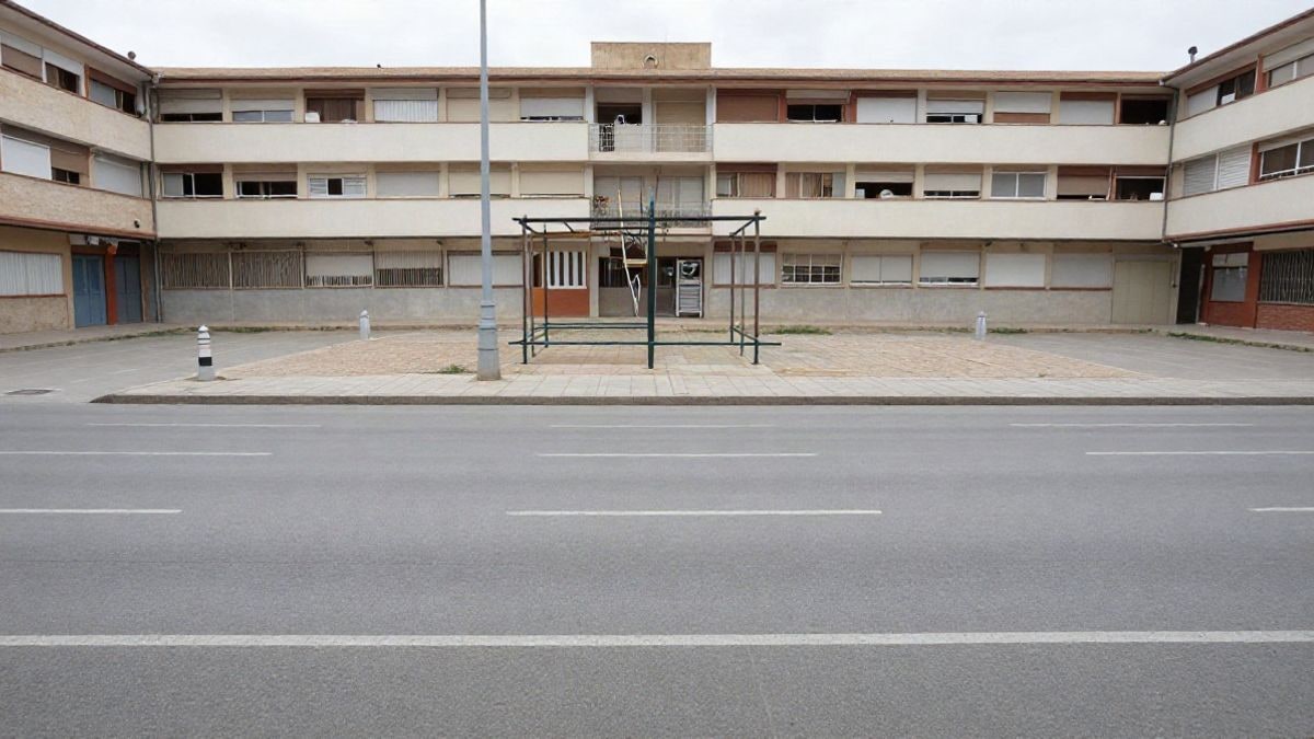 Imagen ilustrativa: fachada de un edificio escolar genérico con patio vacío en un día nublado