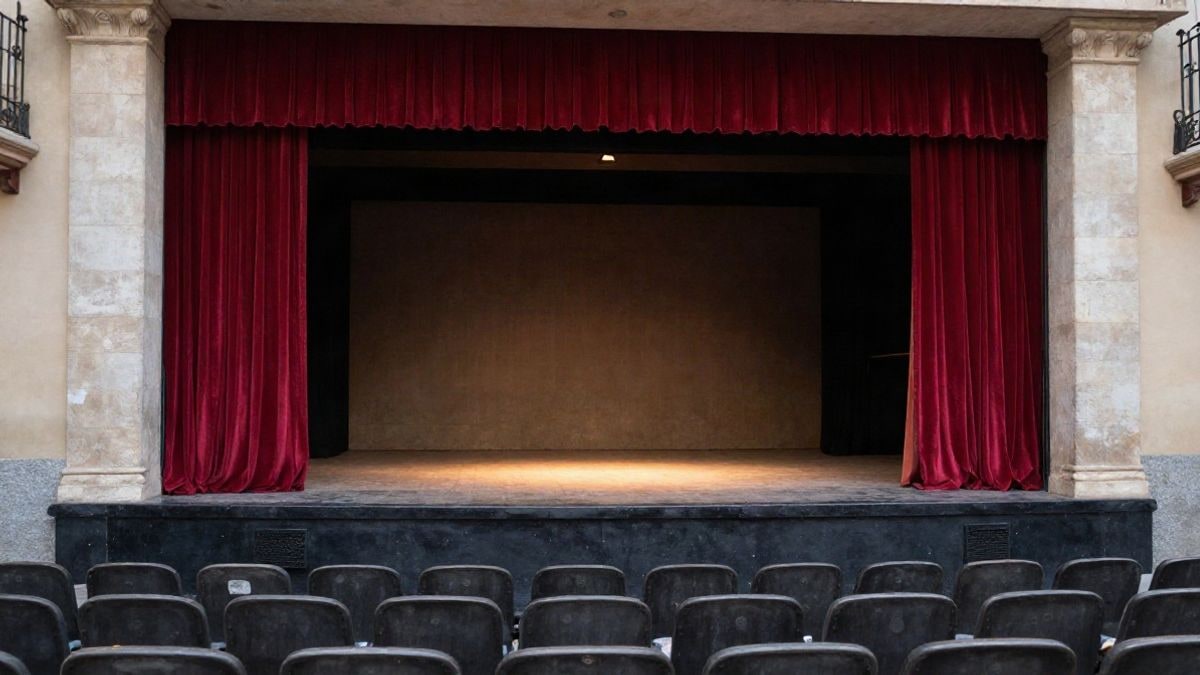 Imagen ilustrativa: escenario de un teatro municipal con cortinas rojas y butacas vacías