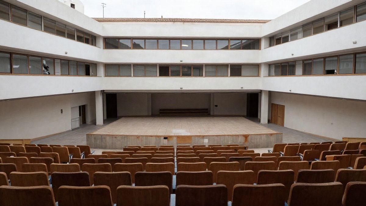 Imagen ilustrativa: interior de un auditorio vacío con filas de butacas y un escenario al fondo, iluminado con luz natural.