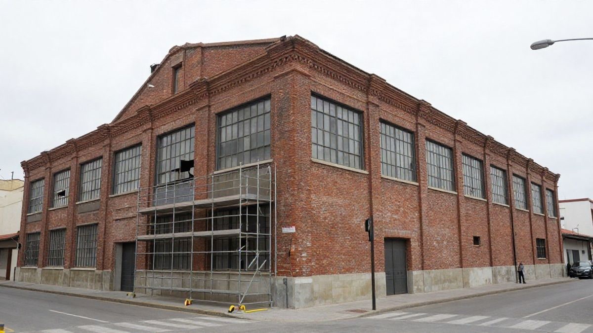 Imagen ilustrativa: fachada de un edificio industrial antiguo con andamios y vallas de obra