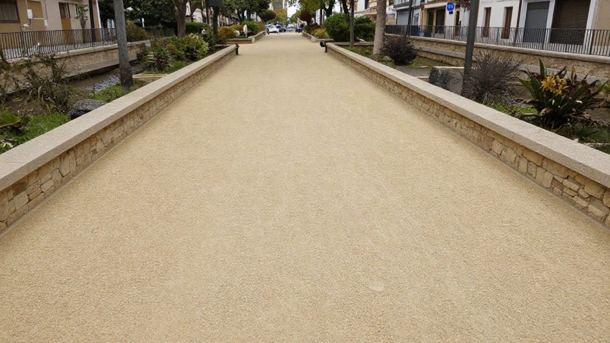 Imagen ilustrativa: camino de parque urbano pavimentado con grava compactada junto a una barandilla