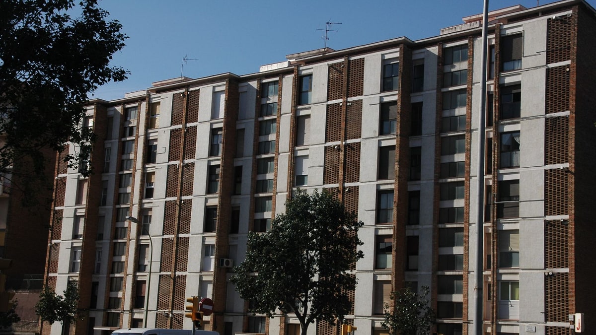 Bloque de viviendas de ladrillo y hormigón con coches aparcados en una calle de Nou Barris