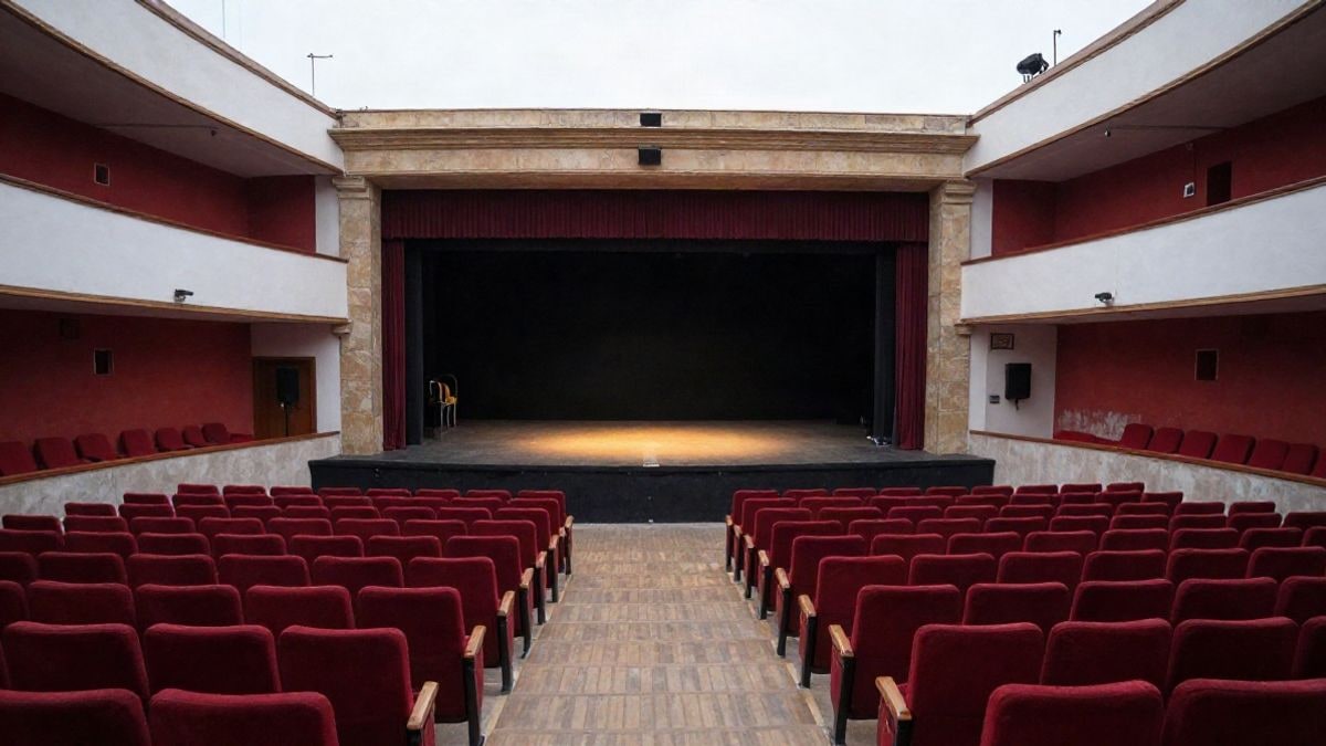 Imagen ilustrativa: escenario vacío de un teatro con butacas rojas y un foco de luz sobre las tablas