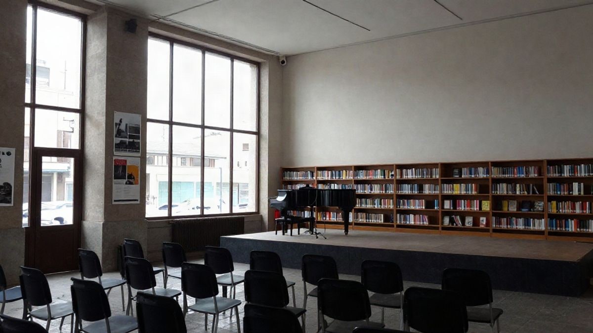 Imagen ilustrativa: interior de un centro cultural con ventana lateral, escenario con piano y sillas