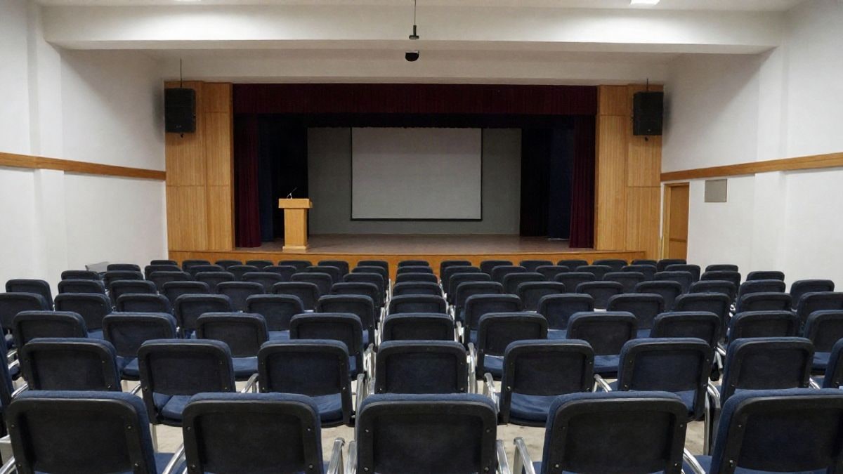 Imagen ilustrativa: interior de un auditorio vacío con butacas y un escenario preparado para un acto institucional.