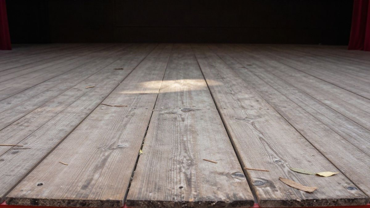 Imagen ilustrativa: detalle de tablones de madera de un escenario con elementos naturales dispersos