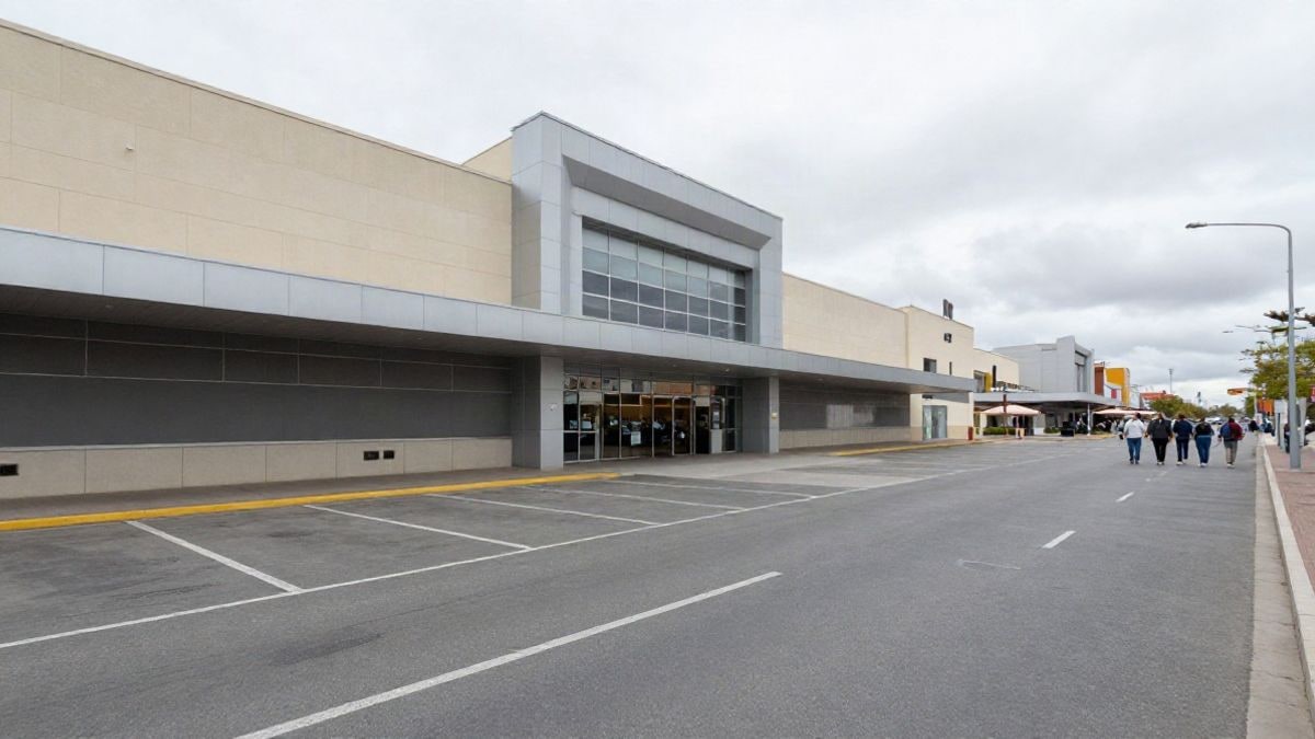 Imagen ilustrativa: fachada genérica de un centro comercial con líneas que convergen hacia la entrada en un día nublado.