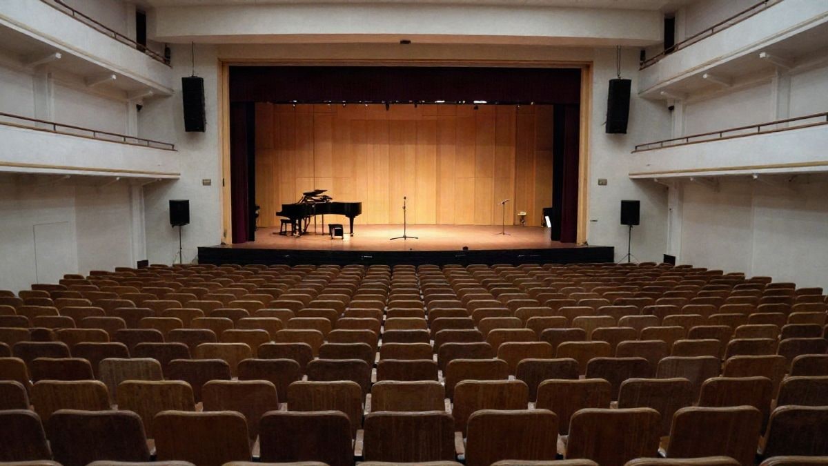 Imagen ilustrativa: sala de conciertos vacía con butacas y un escenario iluminado