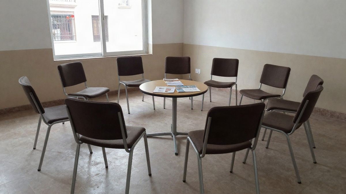 Imagen ilustrativa: sala comunitaria con sillas dispuestas en círculo y folletos informativos sobre una mesa