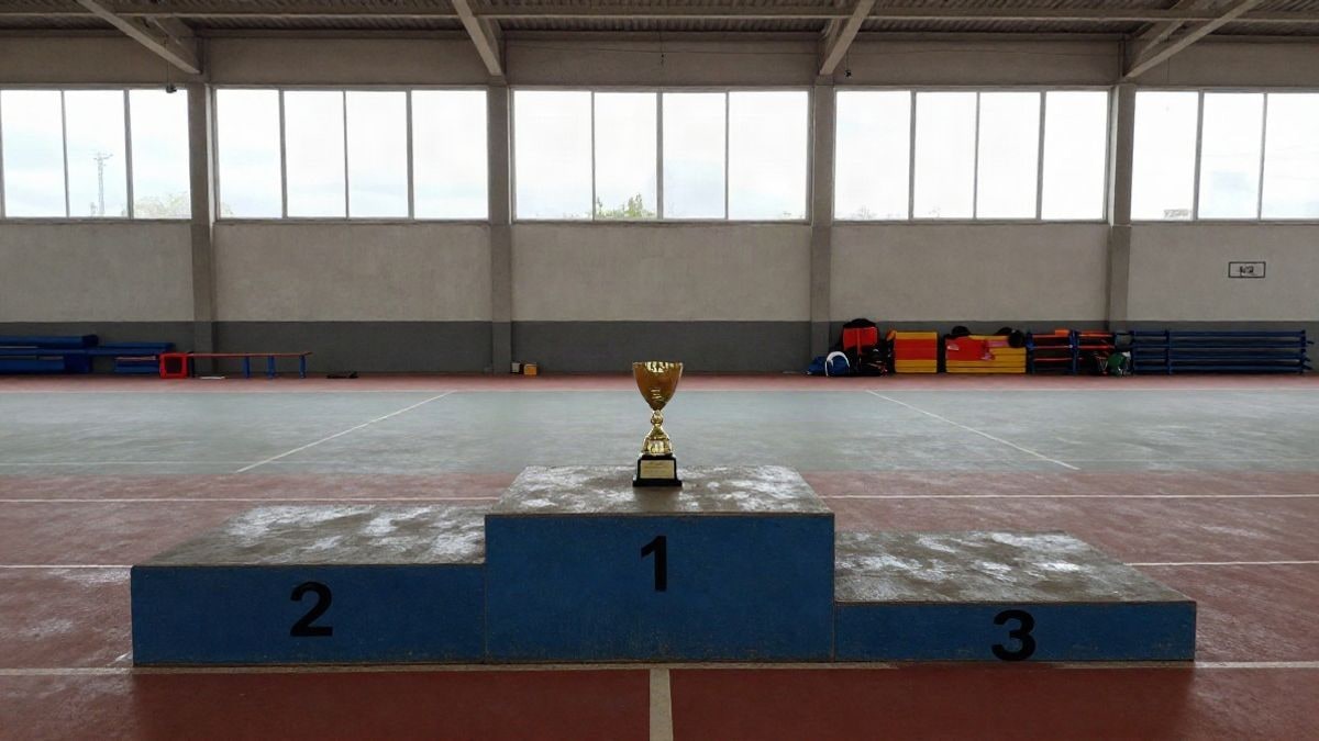 Imagen ilustrativa: un podio deportivo con un trofeo en el escalón más alto, en una sala vacía.