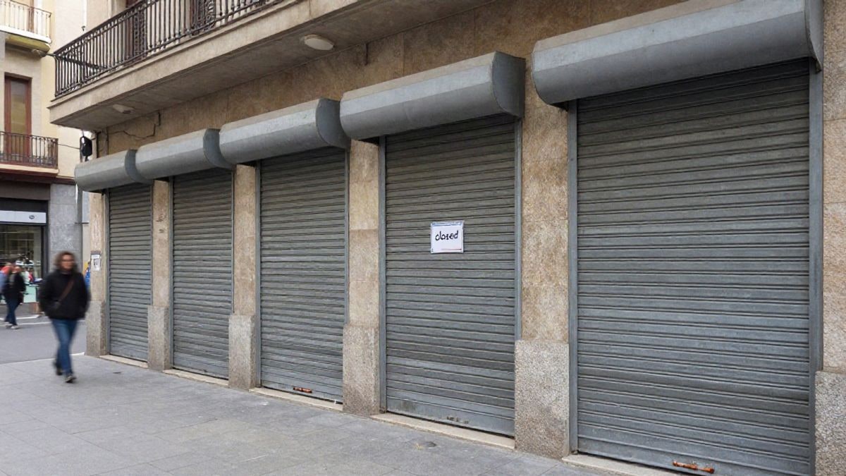 Imagen ilustrativa: persianas metálicas bajadas en la entrada de una biblioteca pública, con un cartel genérico de cerrado.