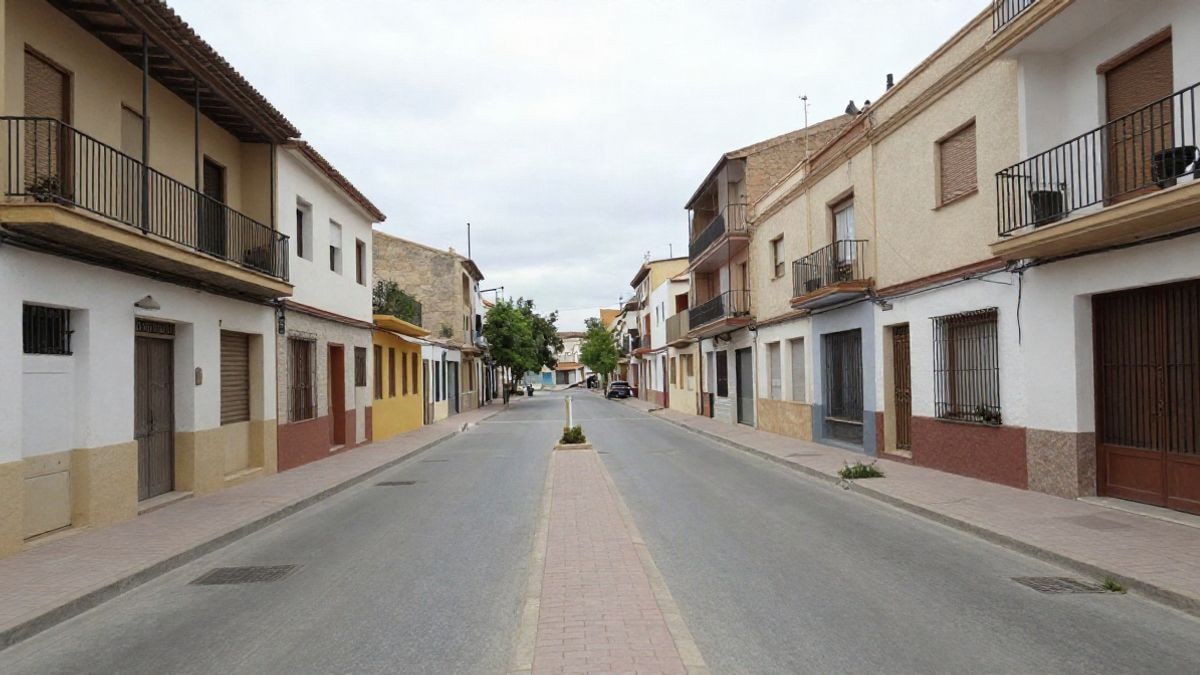 Imagen ilustrativa: calle residencial de un municipio con edificios bajos y una acera que conduce a un parque