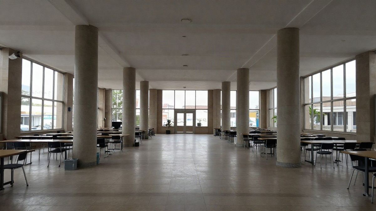 Imagen ilustrativa: interior de una sala pública amplia con columnas y mesas dispuestas para un taller