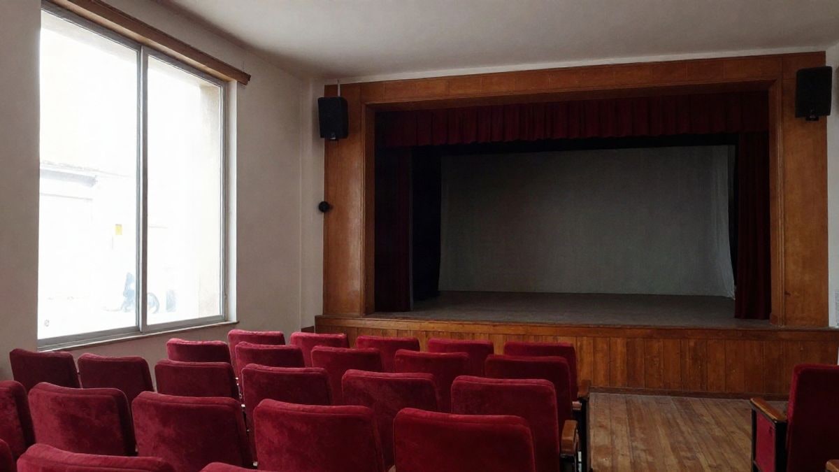 Imagen ilustrativa: escenario de un teatro comunitario con luz lateral de ventana y butacas vacías