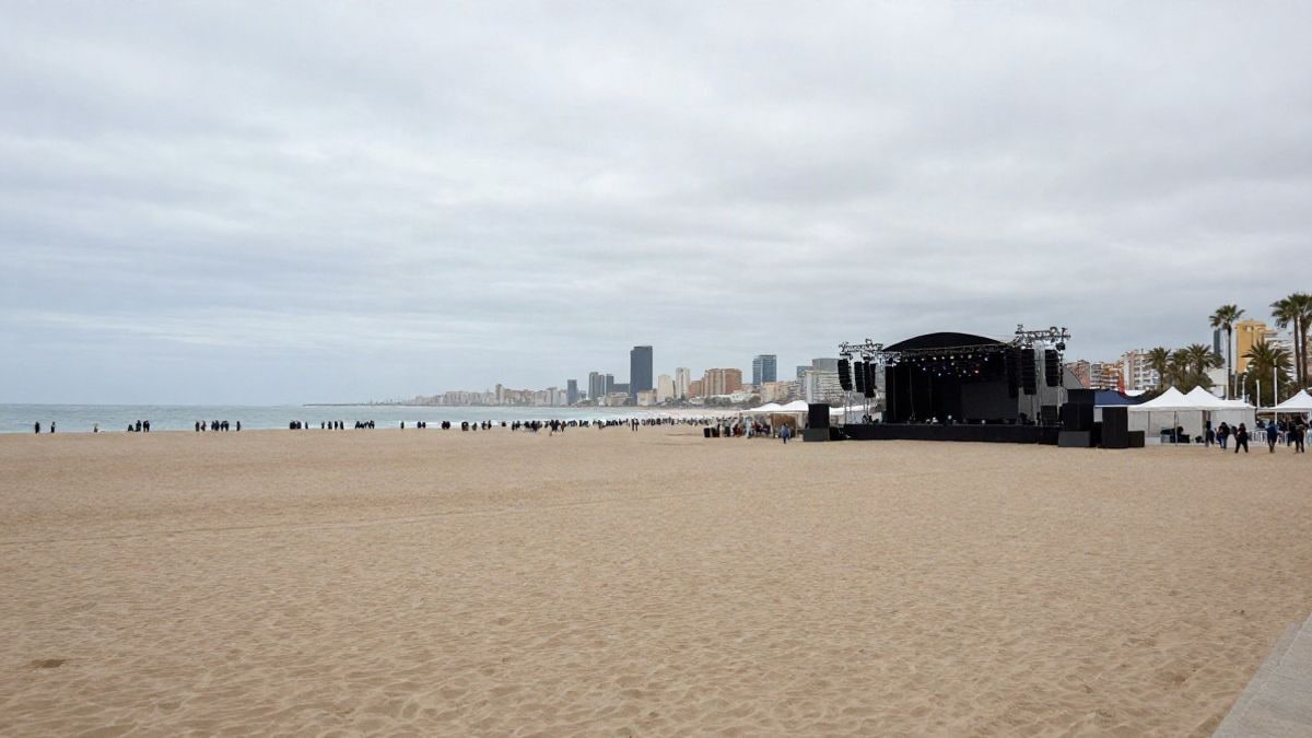 Imagen ilustrativa: una playa urbana con un escenario y fuegos artificiales preparados, con la ciudad al fondo.