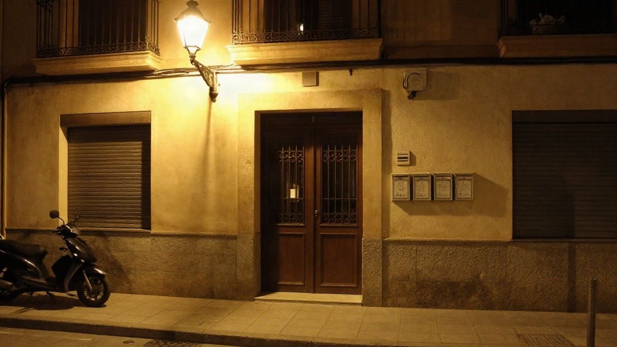 Imagen ilustrativa: portal de un edificio de viviendas de noche con luz artificial en la calle