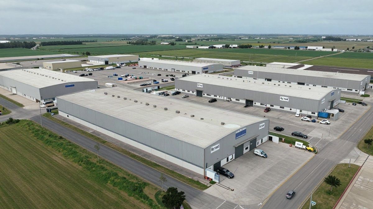 Imagen ilustrativa: vista de un polígono industrial con naves y carteles de alquiler bajo un cielo nublado.