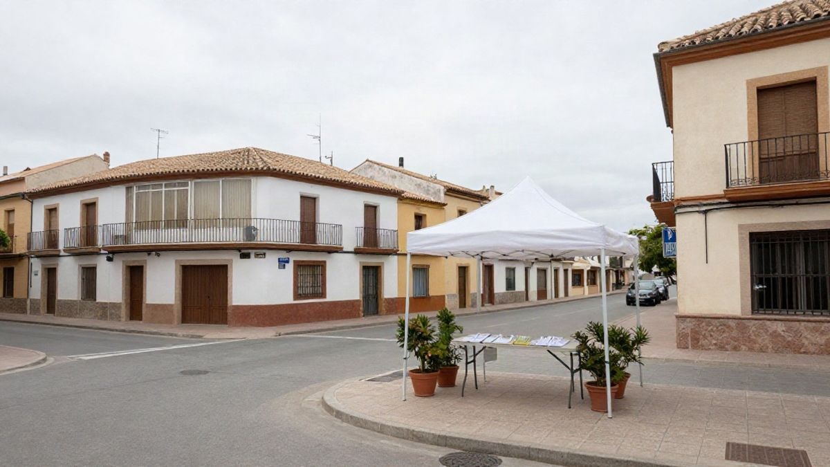 Imagen ilustrativa: carpa informativa en una calle de un municipio español con edificios residenciales al fondo