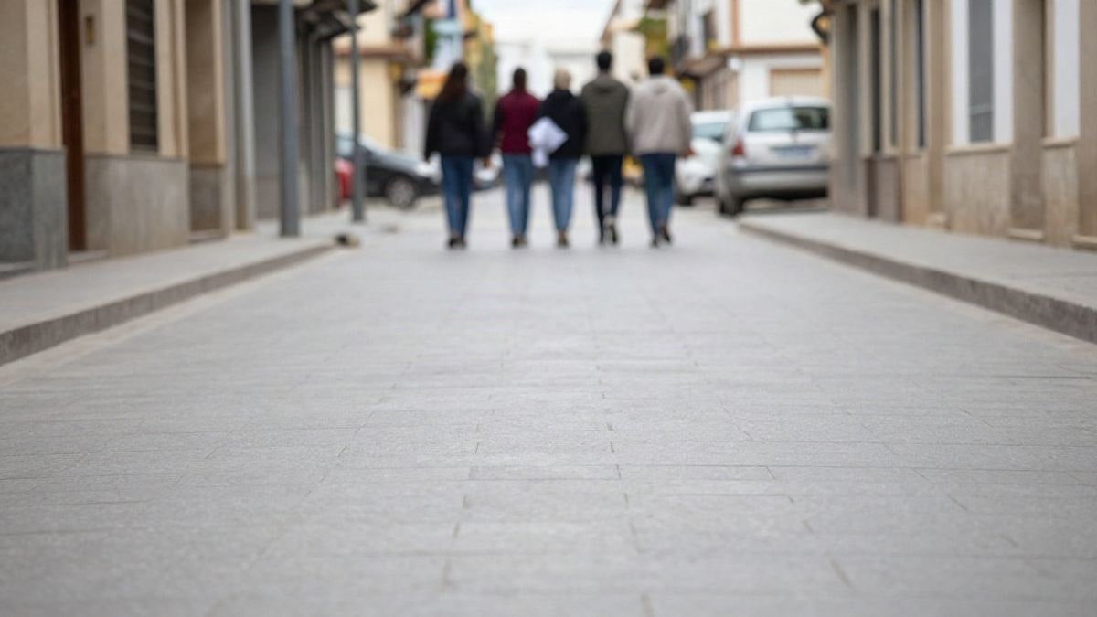 Imagen ilustrativa: grupo de jóvenes de espaldas caminando por una calle corriente con una pancarta doblada
