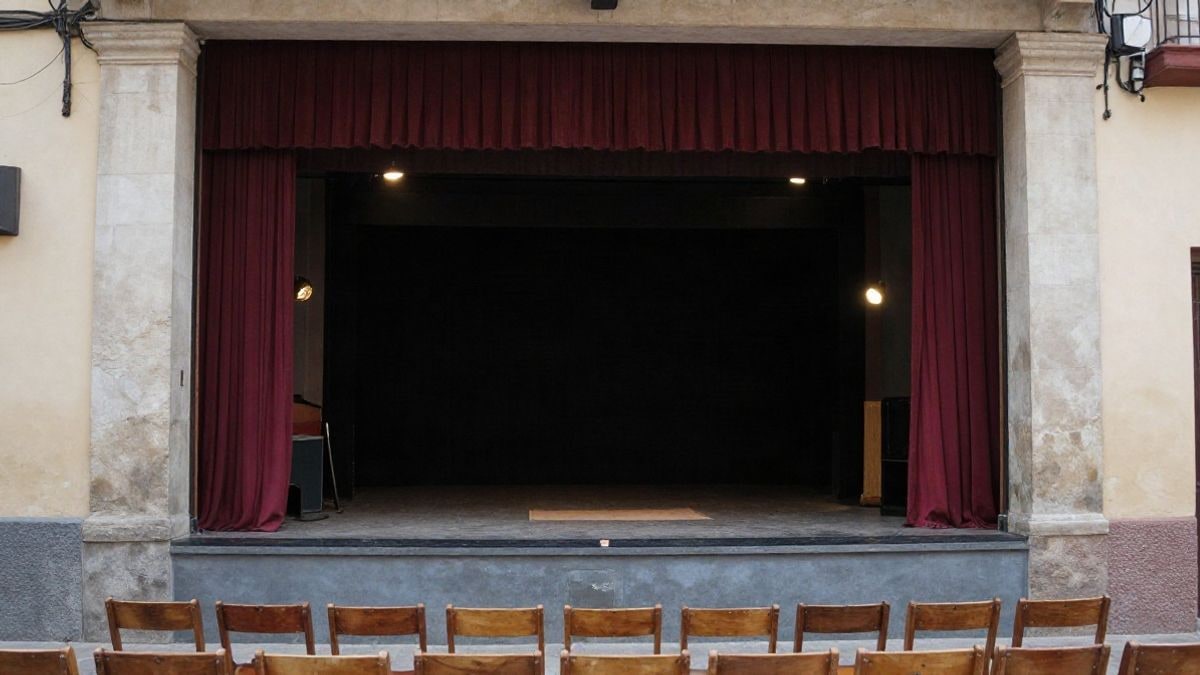 Imagen ilustrativa: interior de un pequeño teatro con el escenario vacío y las luces encendidas.