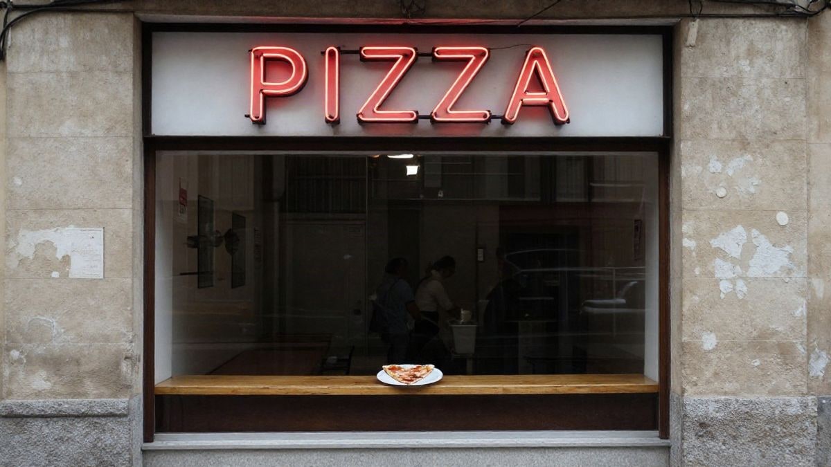 Imagen ilustrativa: fachada de una pizzería con letrero rojo de neón y una porción de pizza en el mostrador