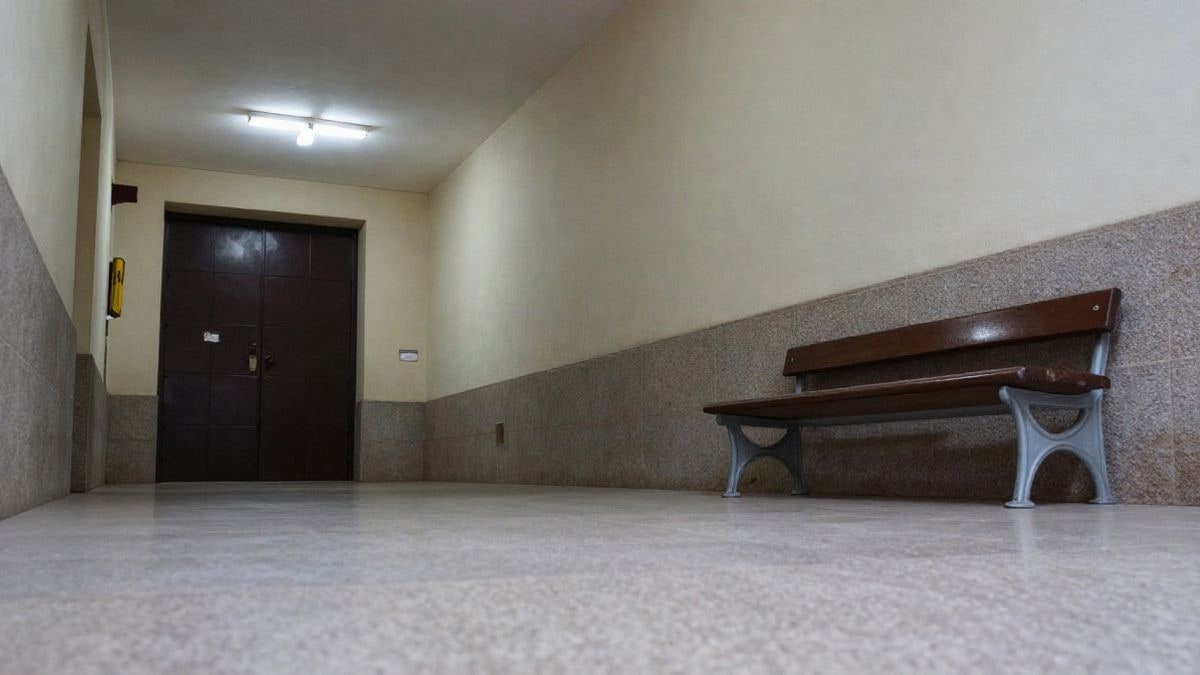 Imagen ilustrativa: pasillo de un juzgado vacío con puerta de madera y banco, luz de día nublado.