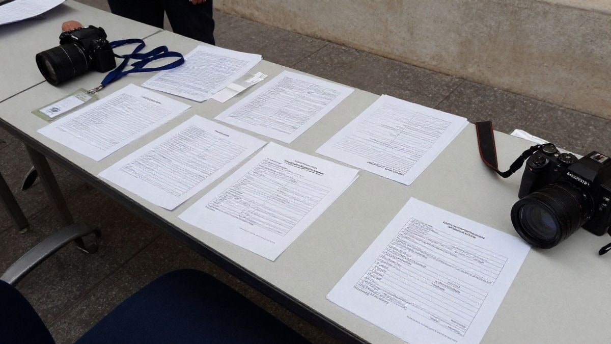 Imagen ilustrativa: mesa con formularios y acreditaciones de prensa en un interior institucional