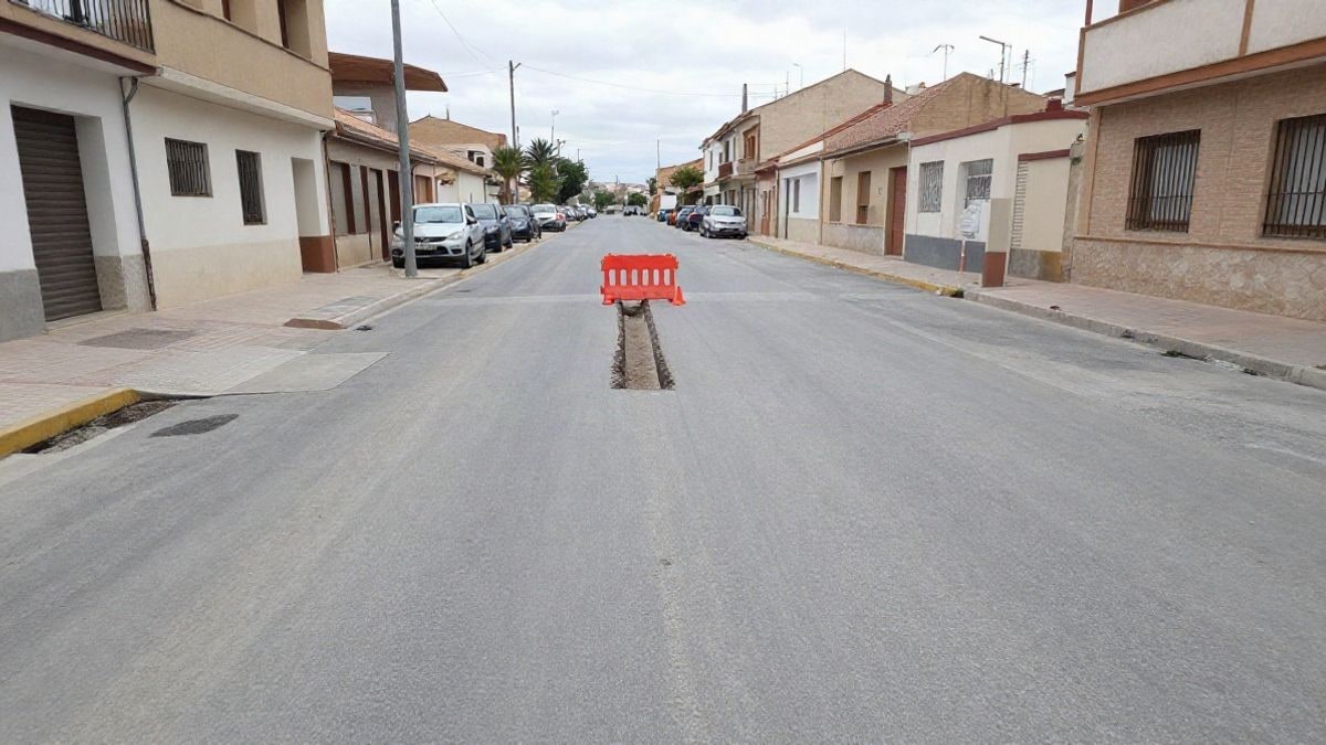 Imagen ilustrativa: una calle con una zanja abierta en el asfalto, conos naranjas y una barrera de obra en un día nublado