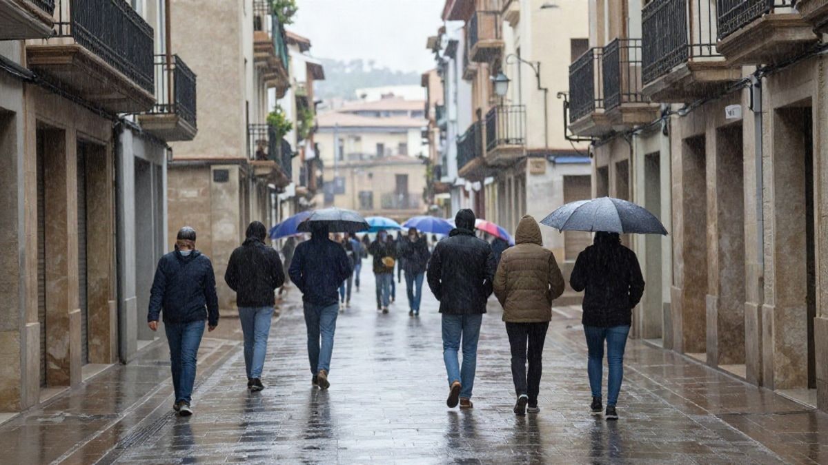 Imagen ilustrativa: calle de un municipio con lluvia intensa y charcos, con nubes oscuras y árboles movidos por el viento.