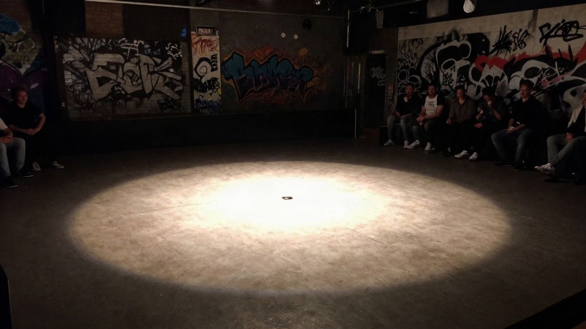 Imagen ilustrativa: pista de baile vacía bajo un foco en un club urbano con grafitis