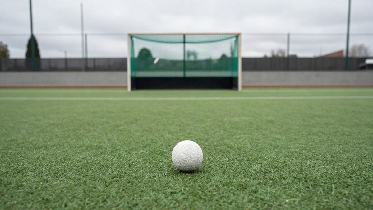 Imagen ilustrativa: un stick de hockey y una bola sobre el césped artificial de un campo de hockey vacío