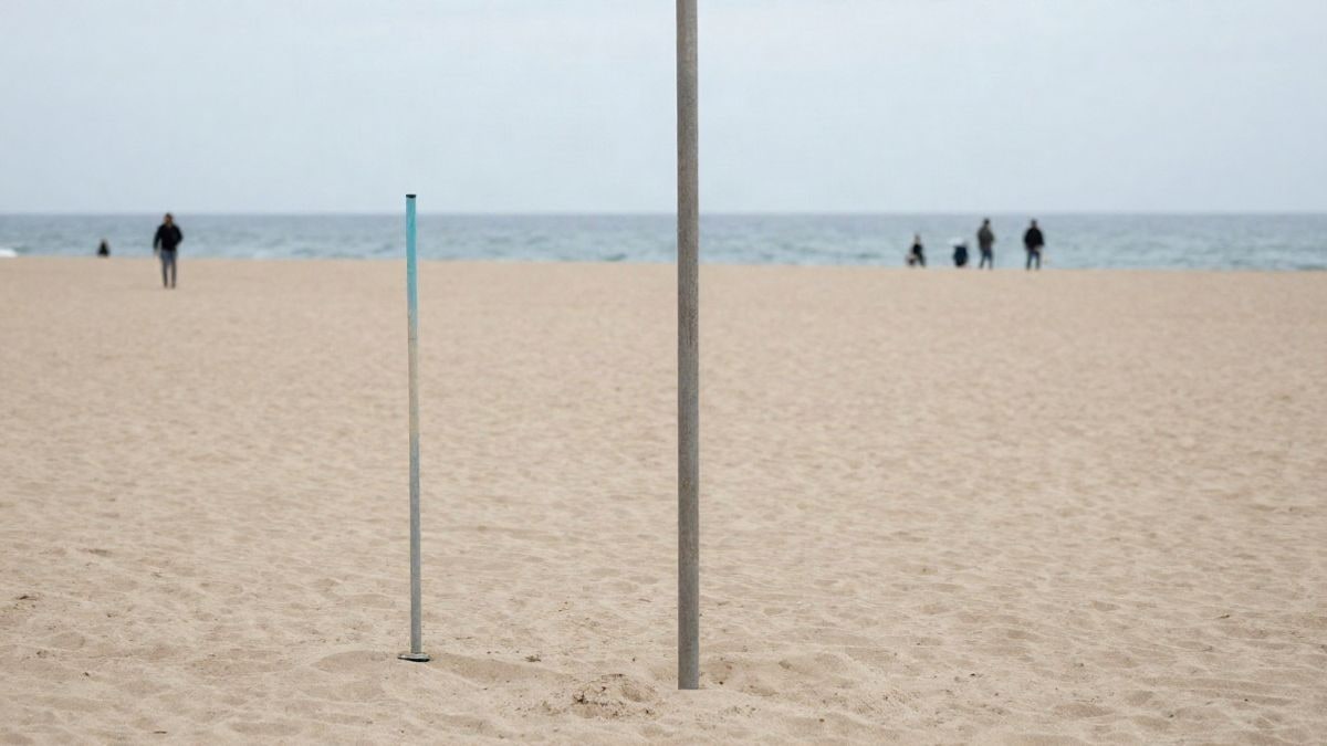 Imagen ilustrativa: bastones de marcha nórdica clavados en la arena de una playa, con el mar al fondo