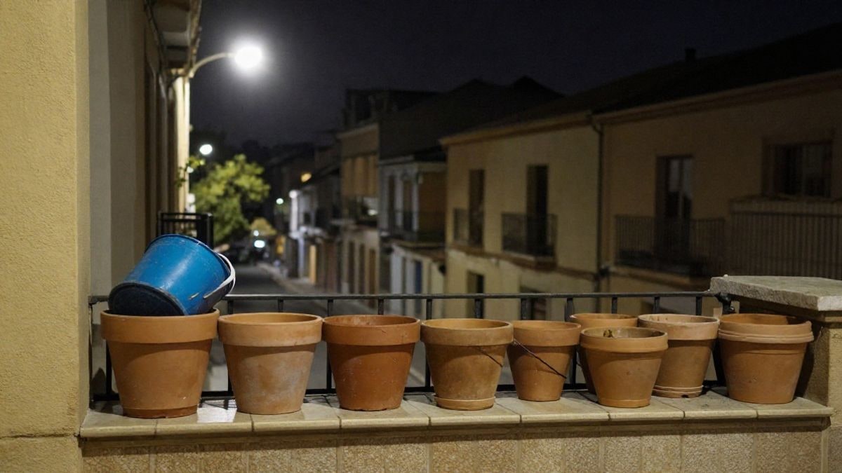 Imagen ilustrativa: macetas vacías y un cubo en un balcón de noche bajo luz artificial