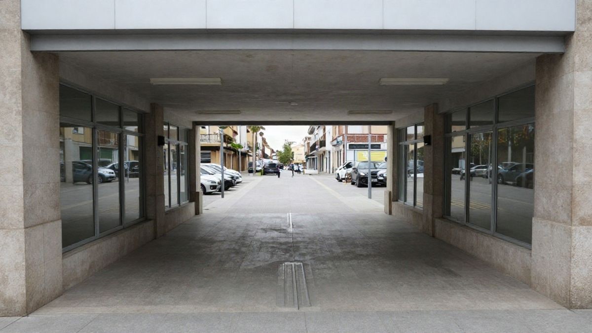 Imagen ilustrativa: entrada de un pabellón deportivo con rampa y puertas de cristal en un día nublado