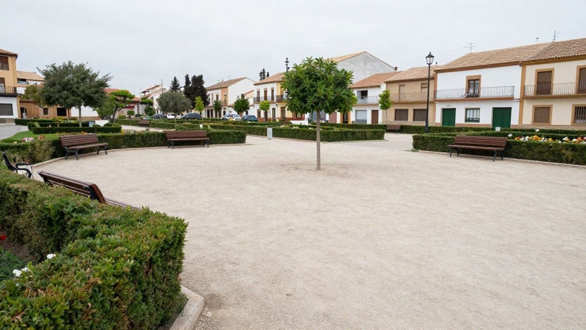 Imagen ilustrativa: parque municipal con bancos vacíos, setos y parterres de flores en un día nublado