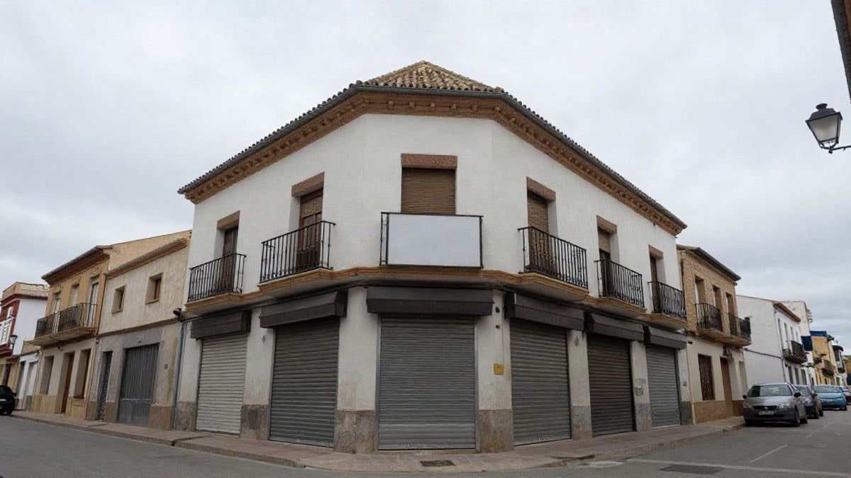Imagen ilustrativa: fachada de un pequeño edificio comercial de barrio con persianas bajadas y cielo nublado