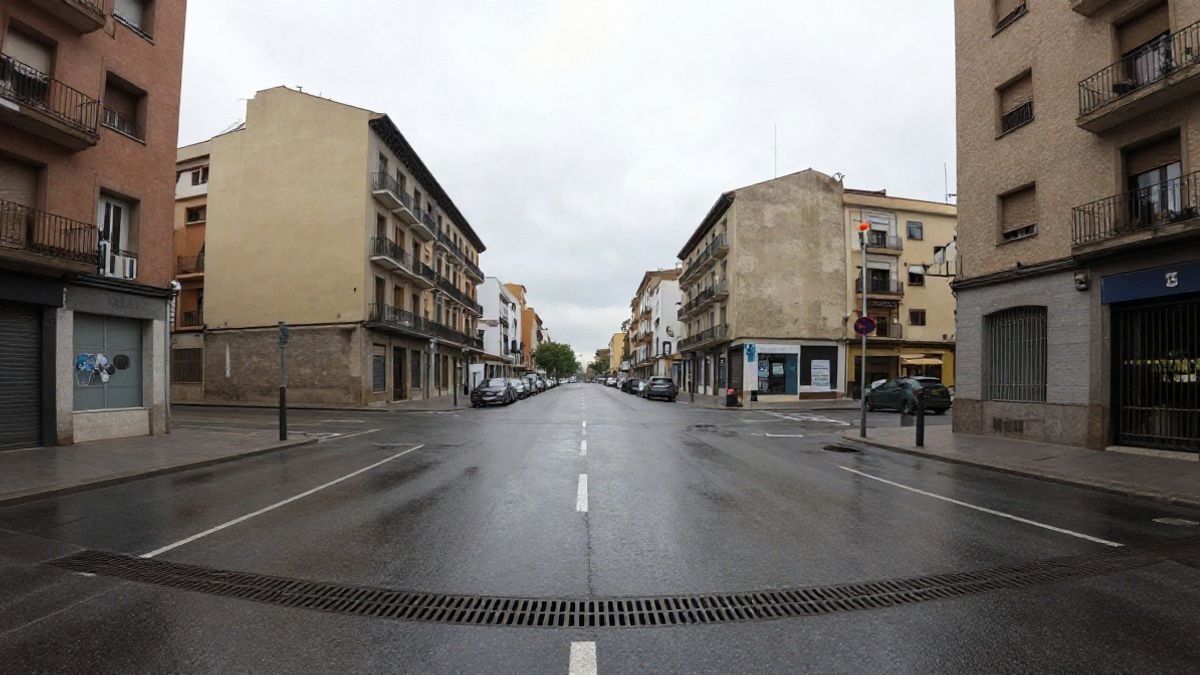 Imagen ilustrativa: calle urbana mojada con líneas que convergen y una rejilla de drenaje en primer plano