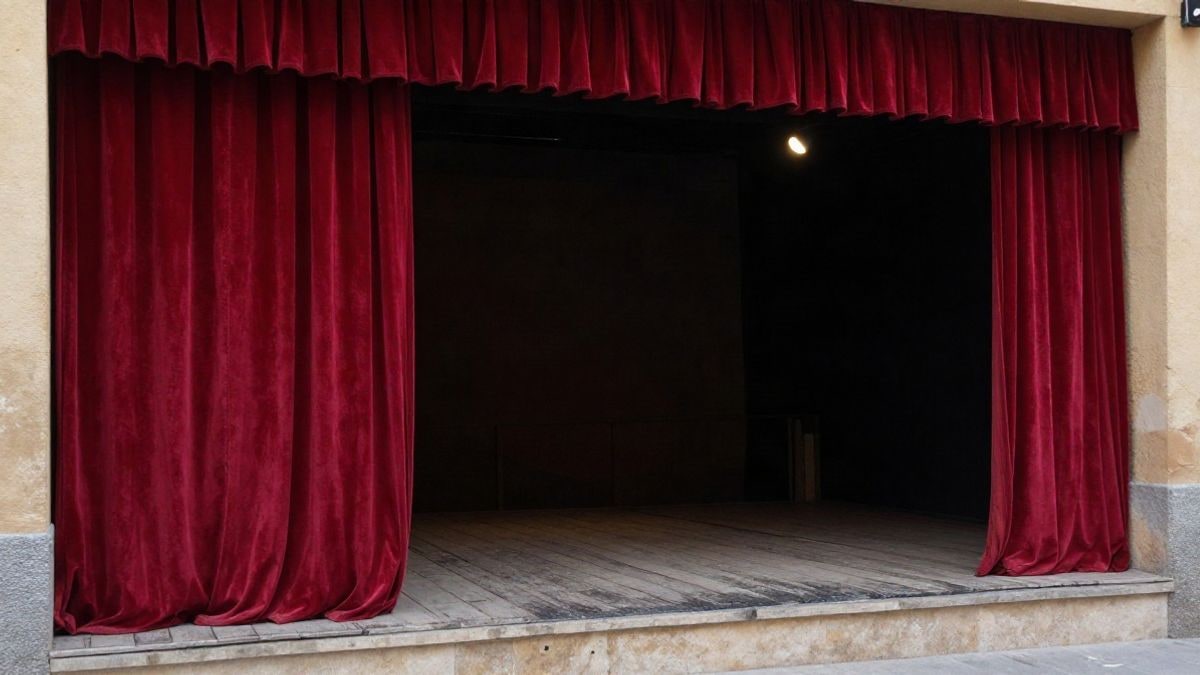 Imagen ilustrativa: escenario de teatro con telón rojo y foco de luz