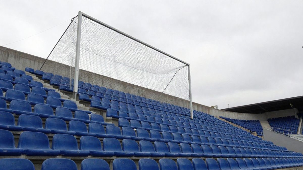 Imagen ilustrativa: vista en contrapicado de una grada de estadio de fútbol vacía con la red de una portería al fondo