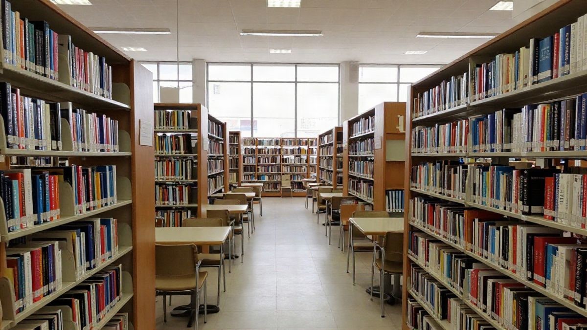 Imagen ilustrativa: interior de una biblioteca pública con estanterías y mesas de lectura vacías