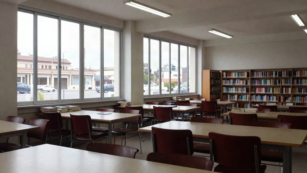 Imagen ilustrativa: sala de lectura de una biblioteca con luz lateral de ventana y mesas vacías