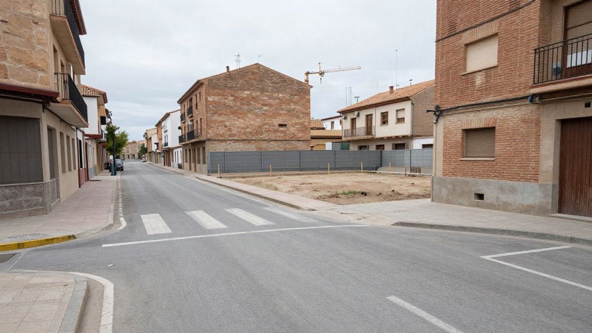 Imagen ilustrativa: solar vacío entre edificios de viviendas en una calle urbana con una grúa al fondo