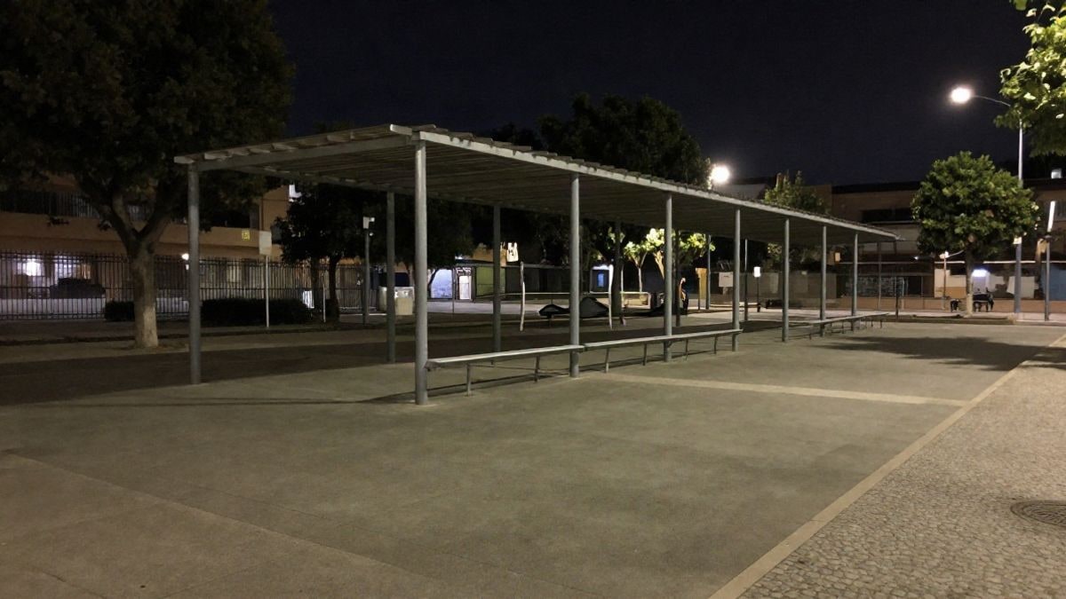 Imagen ilustrativa: patio escolar vacío de noche con una pérgola y luz artificial