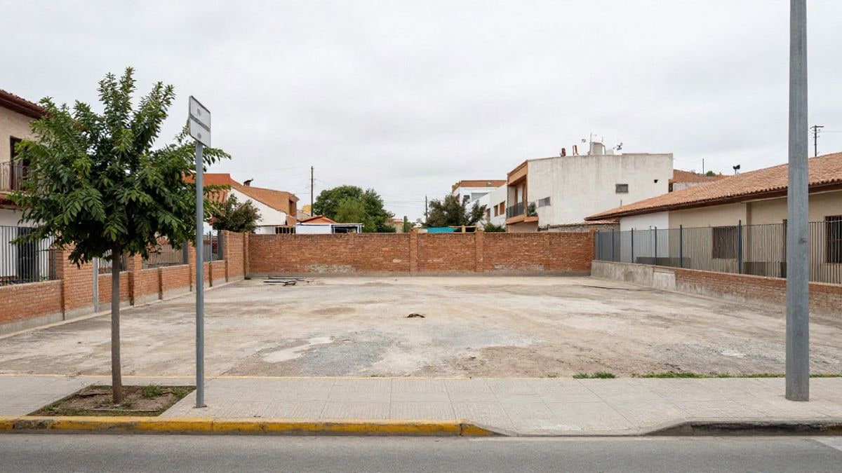 Imagen ilustrativa: solar urbano con valla y muro bajo en un barrio residencial, sin personas ni rótulos