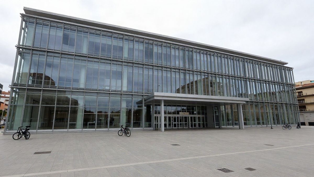 Imagen ilustrativa: ángulo bajo de un edificio moderno de congresos con fachada de cristal y cielo despejado