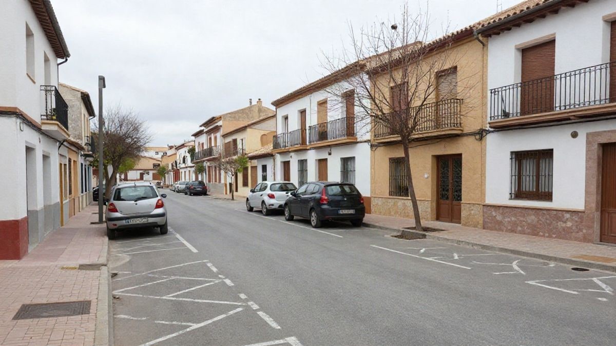 Imagen ilustrativa: una calle residencial con plazas de aparcamiento pintadas en el asfalto y coches estacionados junto a la acera