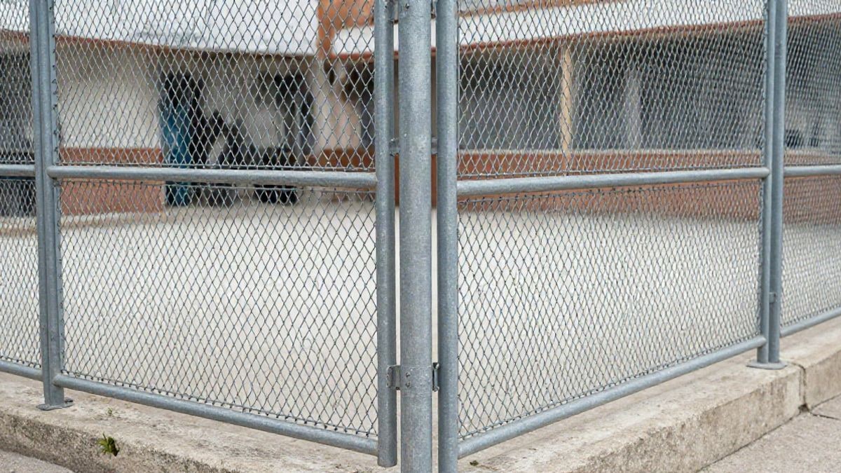 Imagen ilustrativa: detalle de una valla metálica de malla en un patio escolar