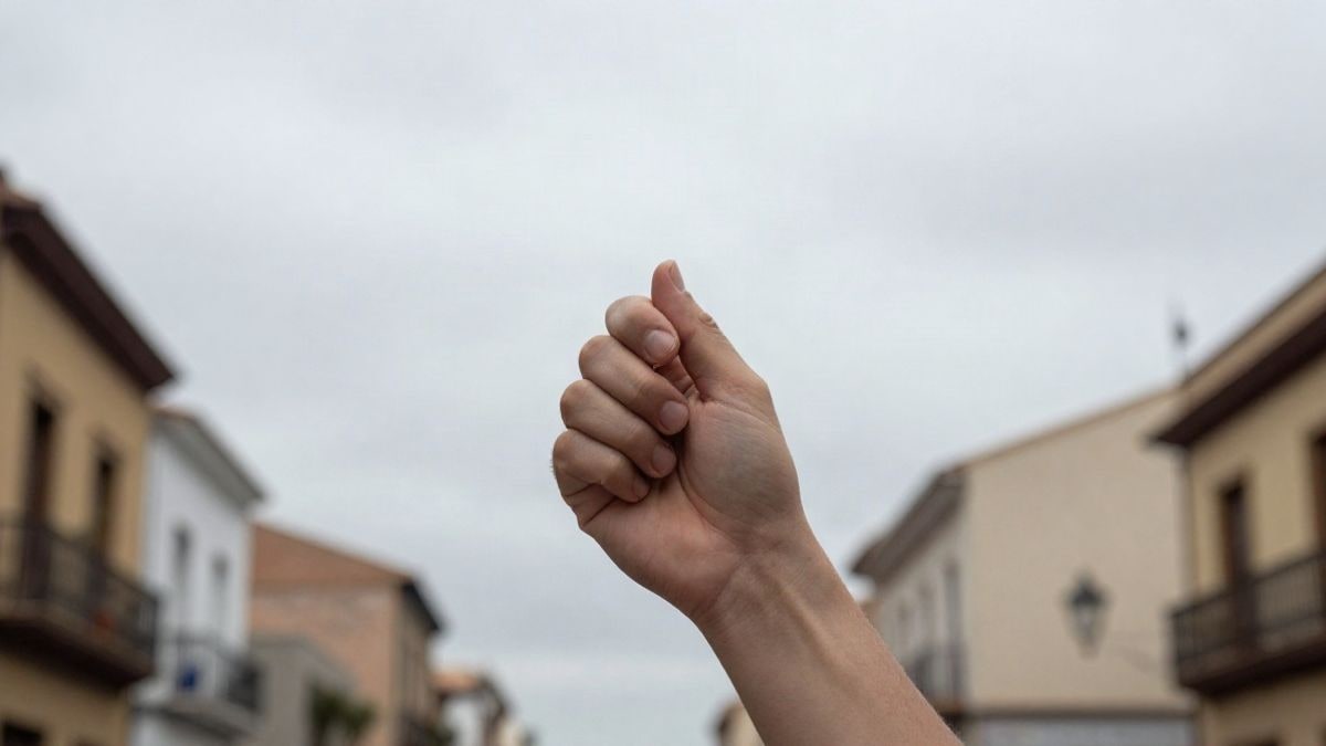 Imagen ilustrativa: mano sosteniendo un móvil con una aplicación del tiempo y nubes de lluvia sobre la ciudad