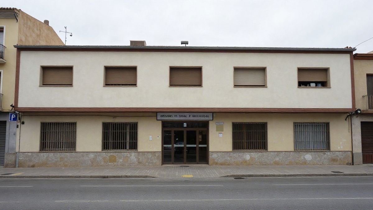 Imagen ilustrativa: fachada genérica de un edificio municipal de servicios sociales en una calle de Badalona, con cielo nublado y sin personas visibles.