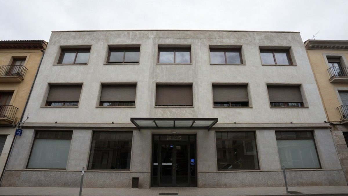 Imagen ilustrativa: fachada sencilla de un edificio municipal con grandes ventanales bajo un cielo nublado